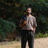 man in a grey linen T-shirt standing in a field