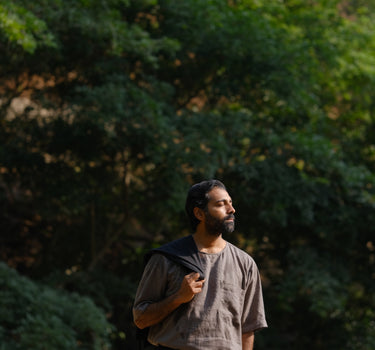 closer look of a man in a grey linen T-shirt standing in a field