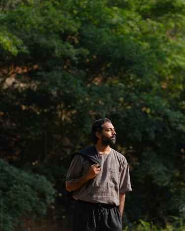 closer look of a man in a grey linen T-shirt standing in a field