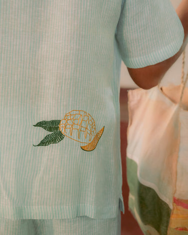 Detailed back view of green and white stripes linen shirt with embroidered mango.