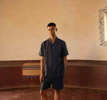 A man in eco-friendly, buds in blue hand-embroidered linen shirt in a yoga hall. half sleeves shirt, Material: linen, front view