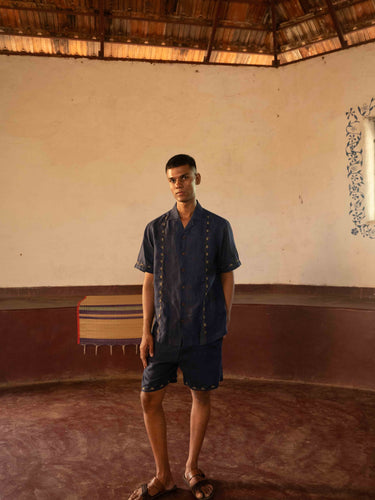 A man in eco-friendly, buds in blue hand-embroidered linen shirt in a yoga hall. half sleeves shirt, Material: linen, front view