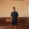 A man in eco-friendly, buds in blue hand-embroidered linen shirt in a yoga hall. half sleeves shirt, Material: linen, front view