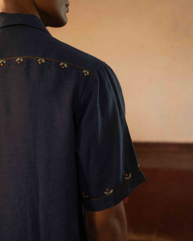 A man in eco-friendly, buds in blue hand-embroidered linen shirt in a yoga hall. half sleeves shirt, Material: linen, back detailed view