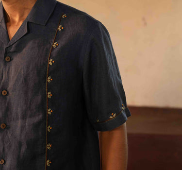 A man in eco-friendly, buds in blue hand-embroidered linen shirt in a yoga hall. half sleeves shirt, Material: linen, front detailed view