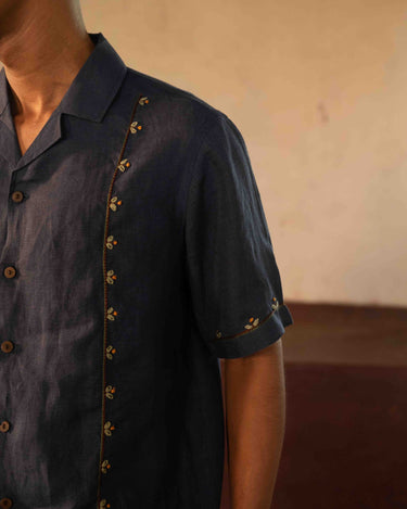 A man in eco-friendly, buds in blue hand-embroidered linen shirt in a yoga hall. half sleeves shirt, Material: linen, front detailed view