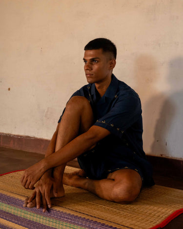 A man in eco-friendly, buds in blue hand-embroidered linen shirt in a yoga hall. half sleeves shirt, Material: linen, front view