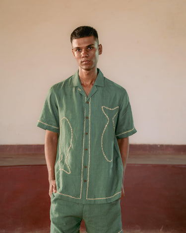 man in eco-friendly Green fish hand-embroidered  linen shirt standing in a yoga hall. Half sleeve shirt, Material: linen, Front view