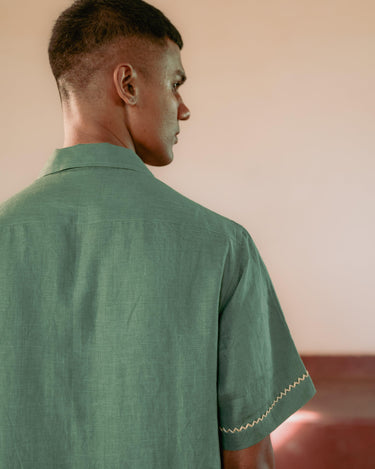 Sleeve border zig and zag embroidery detail of a man wearing a green linen shirt 