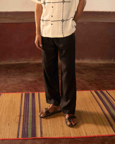 A man standing in a yoga hall wearing black linen lounge pants. Front view