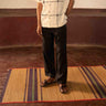 A man standing in a yoga hall wearing black linen lounge pants. Front view