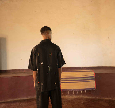 A man in eco-friendly, wild sprigs hand-embroidered linen shirt in a yoga hall. half sleeves shirt, Material: linen, back view