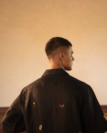 A man in eco-friendly, wild sprigs hand-embroidered linen shirt in a yoga hall. half sleeves shirt, Material: linen, back view