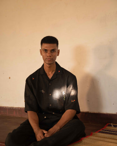 A man in eco-friendly, wild sprigs hand-embroidered linen shirt in a yoga hall. half sleeves shirt, Material: linen, front view