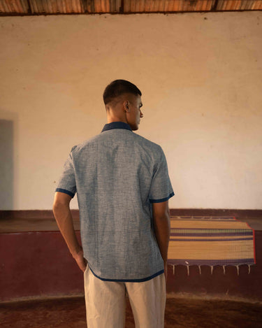 A man in eco-friendly, shades of blue patchwork cotton shirt in a yoga hall. half sleeves shirt, Material: cotton, back view