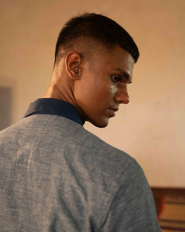 A man in eco-friendly, shades of blue patchwork cotton shirt in a yoga hall. half sleeves shirt, Material: cotton, back view