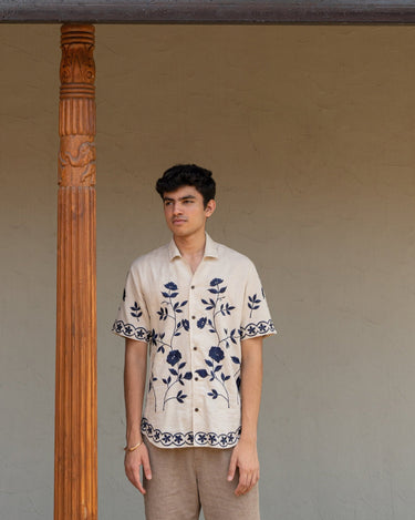 a man wearing beige linen blue floral hand embroidered shirt.