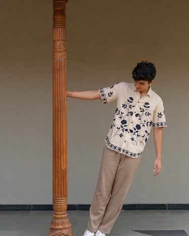 a man wearing beige linen blue hand-embroidered flora shirt 